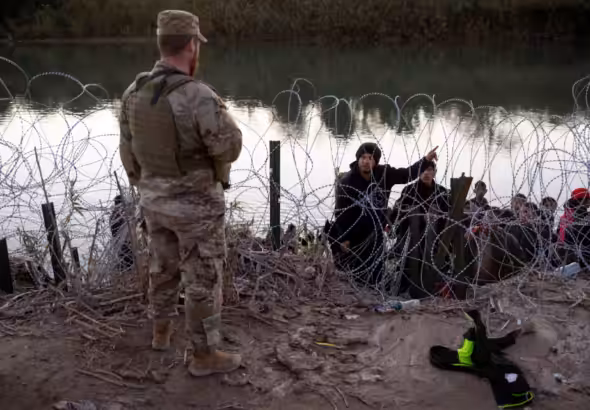 A migrant from Venezuela asks a Texas National guardsman directions to a processing center after crossing from Mexico into the United States on Dec. 17, 2023 in Eagle Pass, Tex. Photo: John Moore/Getty Images.
