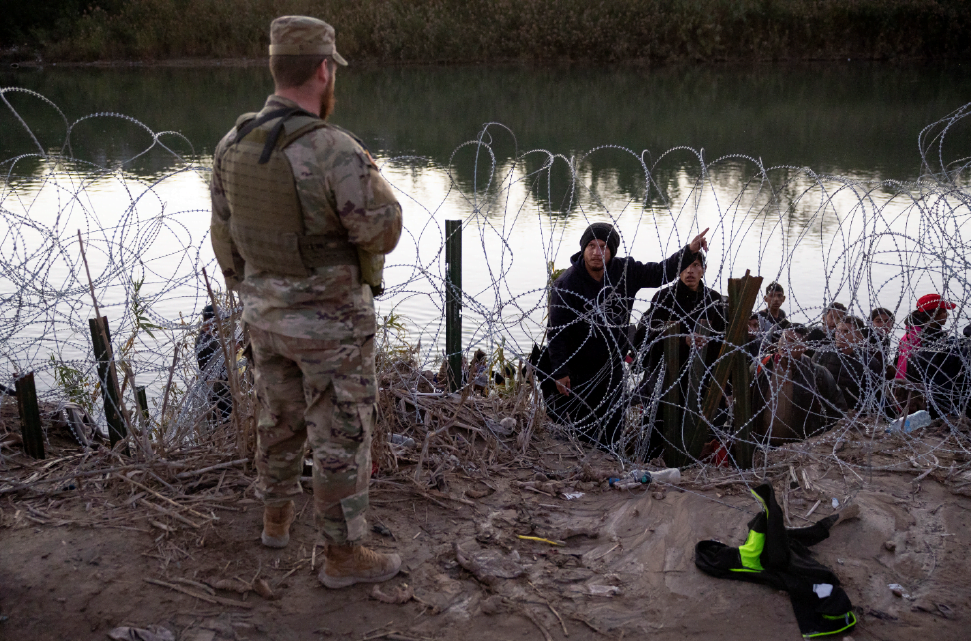 A migrant from Venezuela asks a Texas National guardsman directions to a processing center after crossing from Mexico into the United States on Dec. 17, 2023 in Eagle Pass, Tex. Photo: John Moore/Getty Images.