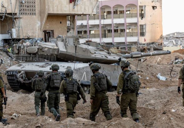 Israeli army personnel and a tank in a detsroyed neighborhood of Gaza City. Photo: Reuters.