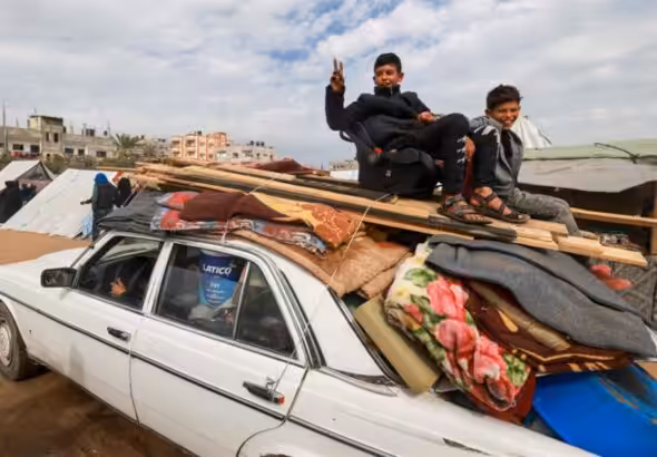 Two Palestinian children ride atop a vehicle in Rafah, February 13, 2024. Photo: Mohammed Abed/AFP.