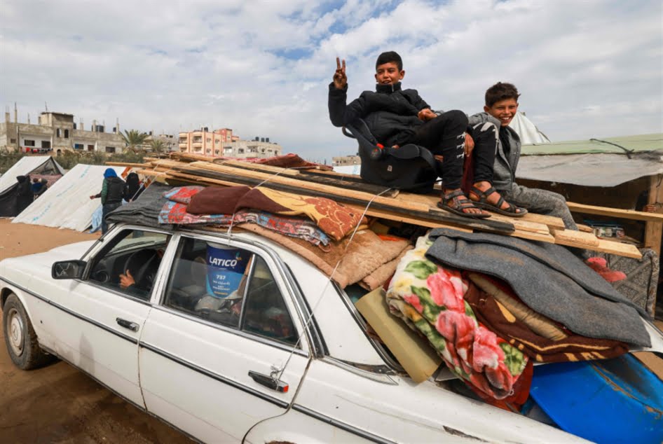Two Palestinian children ride atop a vehicle in Rafah, February 13, 2024. Photo: Mohammed Abed/AFP.