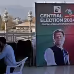 A supporter of Pakistan's imprisoned former Prime Minister, Imran Khan, works on a desk next to a poster of the leader displayed at his party office, in Islamabad, Pakistan, February 9, 2024. Photo: AP.