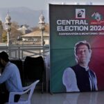 A supporter of Pakistan's imprisoned former Prime Minister, Imran Khan, works on a desk next to a poster of the leader displayed at his party office, in Islamabad, Pakistan, February 9, 2024. Photo: AP.