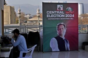 A supporter of Pakistan's imprisoned former Prime Minister, Imran Khan, works on a desk next to a poster of the leader displayed at his party office, in Islamabad, Pakistan, February 9, 2024. Photo: AP.