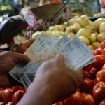 A person counting money at a vegetable market in Venezuela. Photo: Javier Campos/NurPhoto/Gettyimages.ru/File photo.