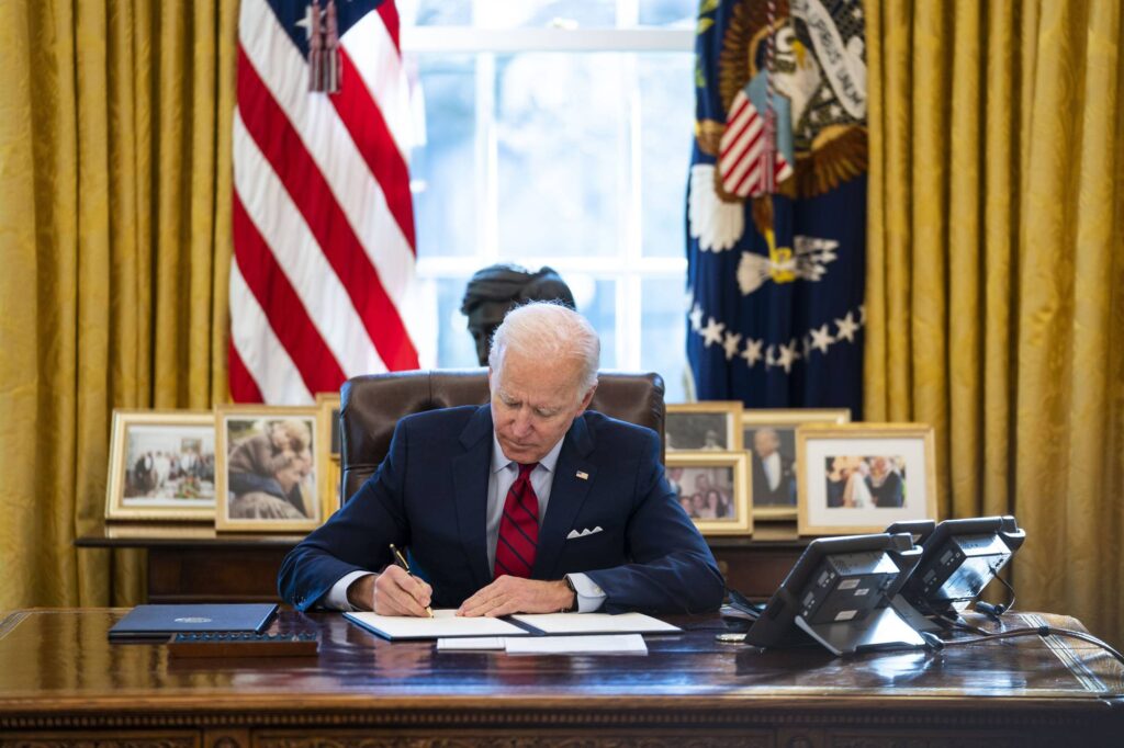 US President Joe Biden signs executive actions in the Oval Office of the White House in Washington on Jan. 26. Photo: Doug Mills/The New York Times.