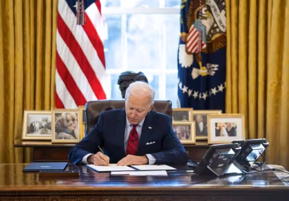 US President Joe Biden signs executive actions in the Oval Office of the White House in Washington on Jan. 26. Photo: Doug Mills/The New York Times.