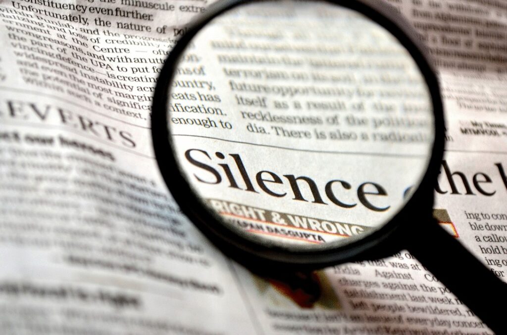 Photo composition showing a newspaper with a magnifying glass where "Silence. right & wrong" can be read. Photo: Pixabay/CC0 1.0.