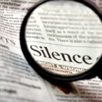 Photo composition showing a newspaper with a magnifying glass where "Silence. right & wrong" can be read. Photo: Pixabay/CC0 1.0.