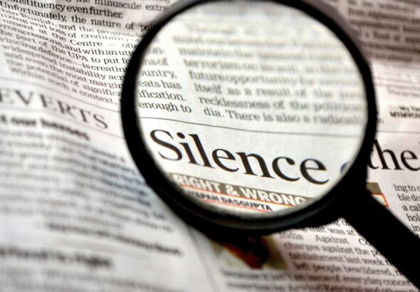 Photo composition showing a newspaper with a magnifying glass where "Silence. right & wrong" can be read. Photo: Pixabay/CC0 1.0.