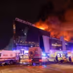 Vehicles of Russian emergency services are parked near the burning Crocus City Hall concert venue following a reported shooting incident, outside Moscow, on Mar. 22, 2024. Photo: Reuters.