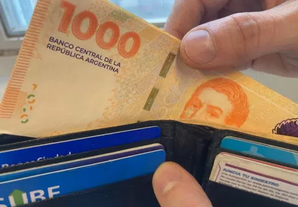 A person taking some Argentinian pesos bank notes from a wallet. Photo: Ariel Grinberg/La Nacion.