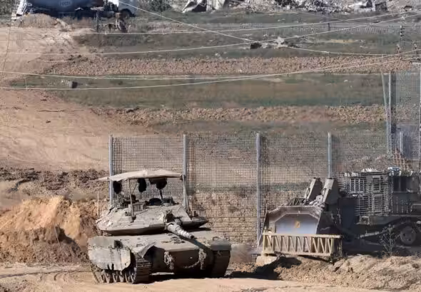 A tank and an armored bulldozer roll along the Israel-Gaza border. Photo: Jack Guez/Agence France-Presse/Getty Images.