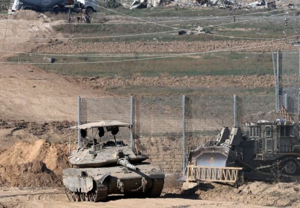 A tank and an armored bulldozer roll along the Israel-Gaza border. Photo: Jack Guez/Agence France-Presse/Getty Images.