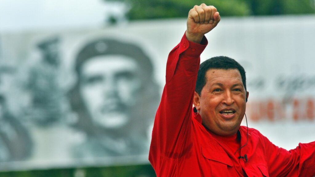 The late president and revolutionary leader of Venezuela, Comandante Hugo Chávez, pictured during a political rally raising his fist, with a billboard featuring Che Guevara in the background. Photo: Sven Creutzmann/Gettyimages.ru/File photo.