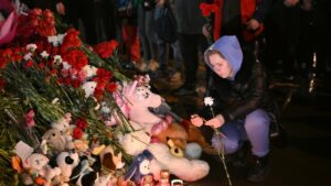 A woman lights a candle at a makeshift memorial near the Crocus City Hall in memory of the victims of a terrorist attack on the concert venue near Moscow on March 22, Russia. Photo: Maksim Blinov/Sputnik.