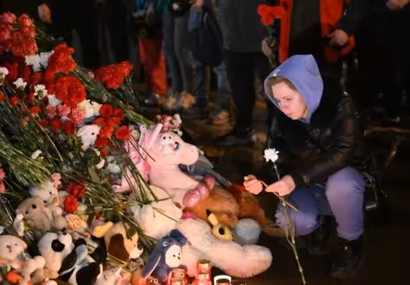 A woman lights a candle at a makeshift memorial near the Crocus City Hall in memory of the victims of a terrorist attack on the concert venue near Moscow on March 22, Russia. Photo: Maksim Blinov/Sputnik.