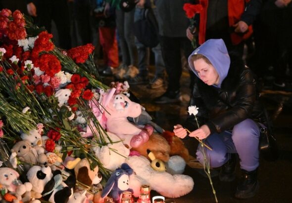 A woman lights a candle at a makeshift memorial near the Crocus City Hall in memory of the victims of a terrorist attack on the concert venue near Moscow on March 22, Russia. Photo: Maksim Blinov/Sputnik.