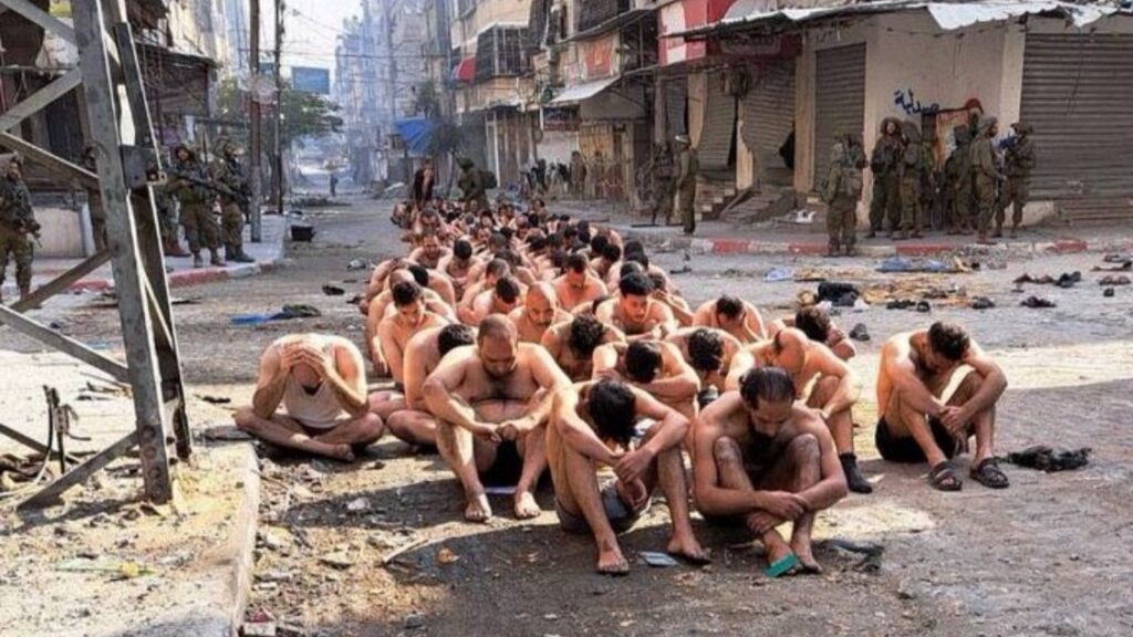 Gaza, dozens of half naked men with eyes covered seat in the middle of the street while guarded by Israeli Occupation Forces. Photo: Reuters.