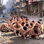 Gaza, dozens of half naked men with eyes covered seat in the middle of the street while guarded by Israeli Occupation Forces. Photo: Reuters.