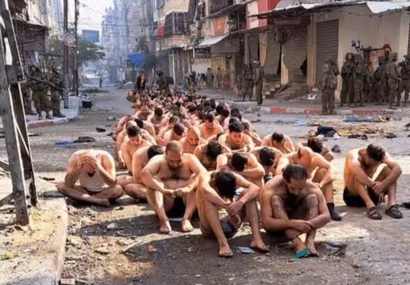 Gaza, dozens of half naked men with eyes covered seat in the middle of the street while guarded by Israeli Occupation Forces. Photo: Reuters.