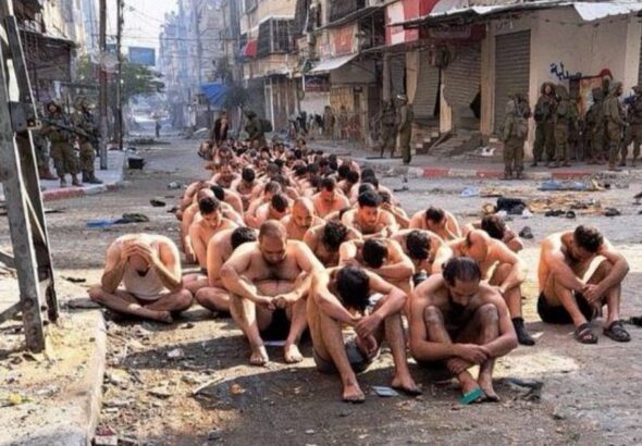 Gaza, dozens of half naked men with eyes covered seat in the middle of the street while guarded by Israeli Occupation Forces. Photo: Reuters.