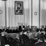 Ben Gurion proclaims the “State of Israel” in a museum in Tel Aviv, under the portrait of Theodor Herzl, founder of the zionist movement, on May 14, 1948. Photo: Wikimedia Commons / Rudi Weissenstein.