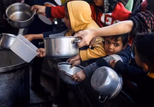 Palestinian children wait to receive food cooked by a charity kitchen amid shortages of food supplies, in Rafah, in the southern Gaza Strip, March 5, 2024. Photo: Mohammed Salem/Reuters.