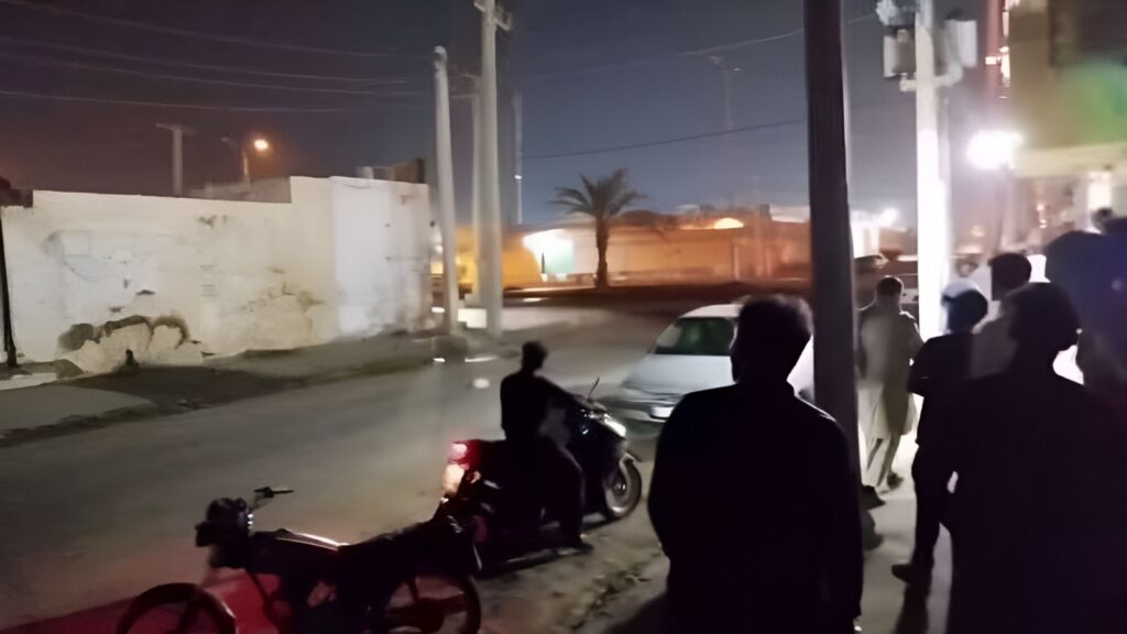 People on a dark street at night looking at something in the distance. Photo: PressTV/File photo.
