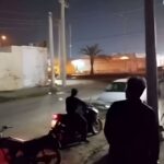 People on a dark street at night looking at something in the distance. Photo: PressTV/File photo.