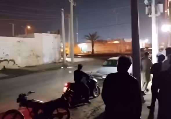People on a dark street at night looking at something in the distance. Photo: PressTV/File photo.