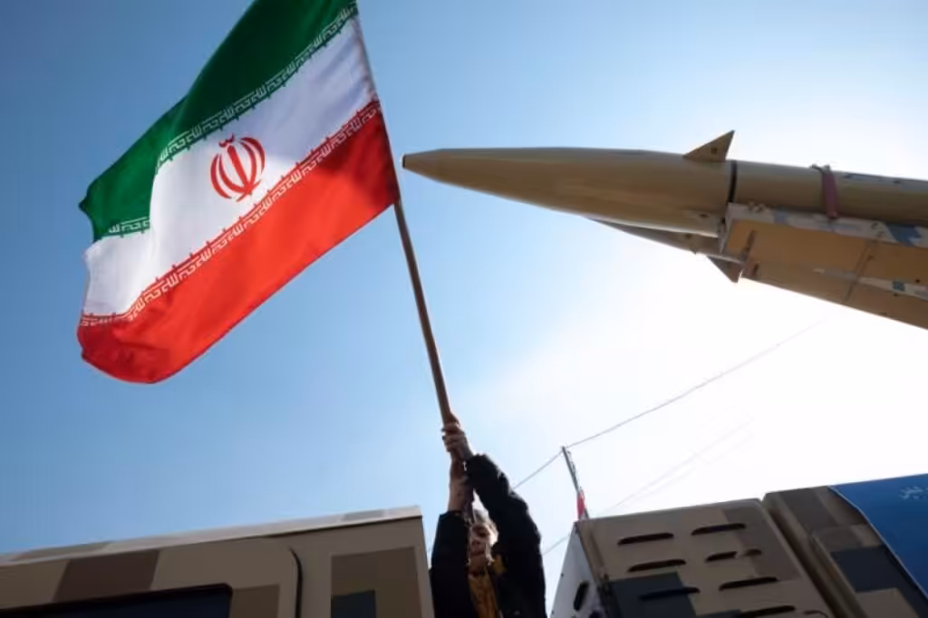 A person holding an Iranian flag next to a missile. Photo: File photo.
