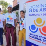 People wearing "2024 National Popular Consultation" t-shirts next to a banner with the logo of the electoral consultation. Photo: Venezuelan Ministry of Science and Technology.