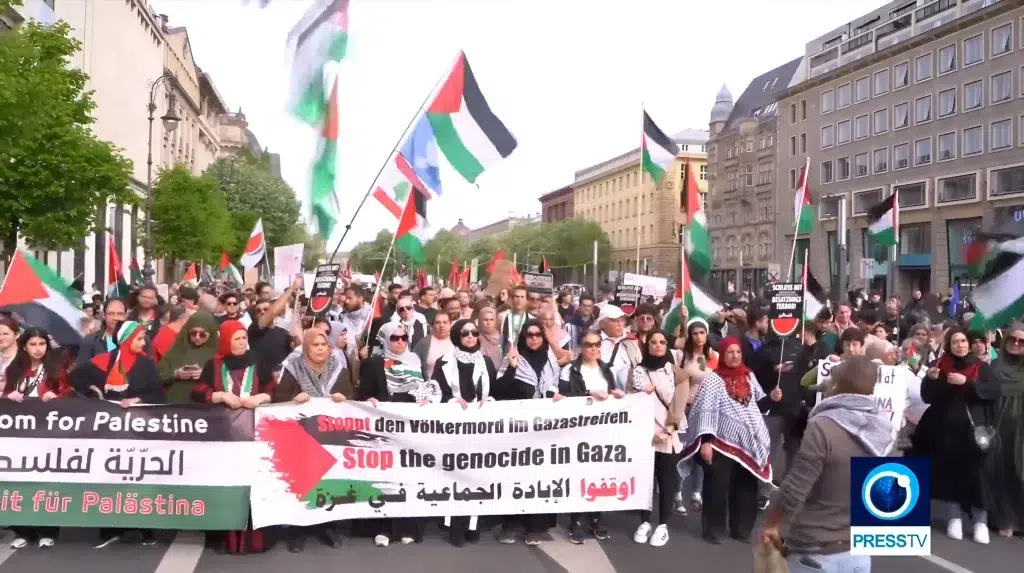 Pro-Palestinian protesters in the streets of Berlin holding a banner that reads “Stop the Genocide in Gaza,” on Sunday, April 14, 2024. Photo: PressTV footage screenshot.