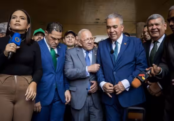 Luis Eduardo Martinez (center-right) buttoning up his suit while Democratic Action's Bernabe Gutierrez (center) talks to him, before issuing statements to the press on Monday, April 22, 2024. Photo: QuePasaMedia.