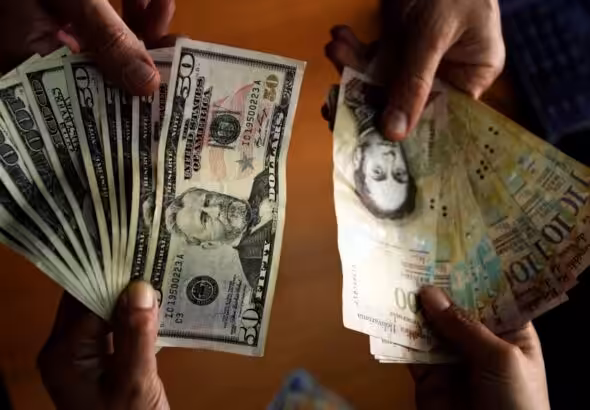 People holding US dollar banknotes and Venezuelan bolívar banknotes. Photo: Juan Barreto/AFP/Getty Images/File photo.