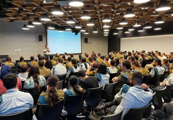 A packed room of Israel Defense Forces (IDF) soldiers attending a conference at a Microsoft Israel R&D center. The photo was publicly shared by the Lotem technology unit of the IDF’s Computer Services Directorate on August 2, 2023 and shows a conference led by the unit’s Shahar component the previous day, with roughly 150 soldiers in attendance. Microsoft’s logo can be partially seen on the center of the left side of the image and the title of the displayed slide translates from Hebrew to “the 10 commandments of the digital.” The second such commandment can be seen to be “RTFM,” meaning: “Read The Fucking Manual.”