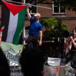 People stand atop a pile of barricades as they lead a chant at an encampment by students protesting against Israel at George Washington University, April 30, 2024. Mark Schiefelbein. Photo: AP.