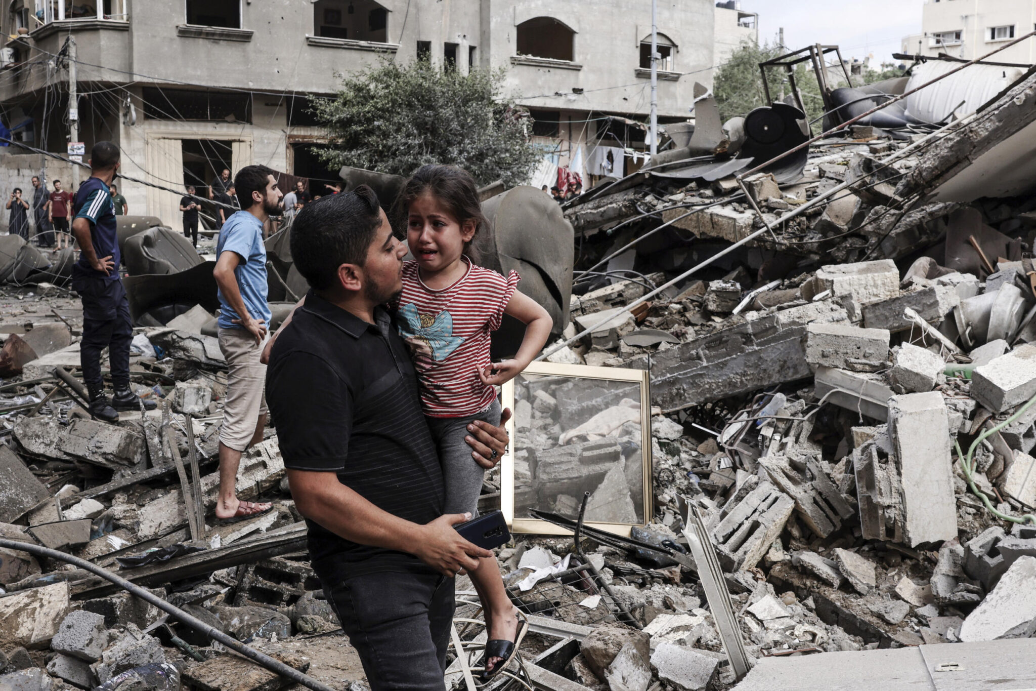 A man carries a crying child amid rubble of a building destroyed in an Israeli air strike in Gaza City. Photo: Mohammed Abed/AFP.