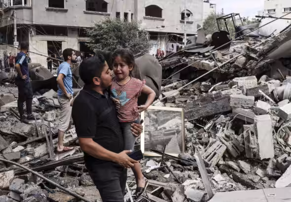 A man carries a crying child amid rubble of a building destroyed in an Israeli air strike in Gaza City. Photo: Mohammed Abed/AFP.