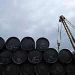A worker checks oil barrels before shipping. Photo: Edgar Su/Reuters.