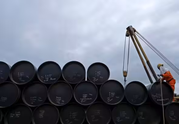 A worker checks oil barrels before shipping. Photo: Edgar Su/Reuters.