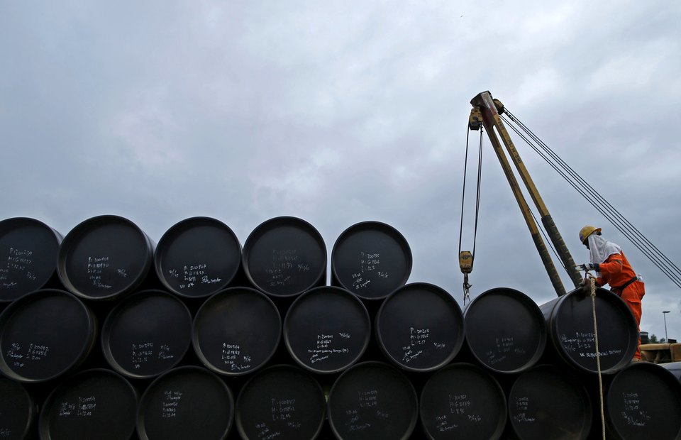 A worker checks oil barrels before shipping. Photo: Edgar Su/Reuters.