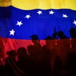 Opposition protesters, seen behind a Venezuelan flag, during the violent opposition protests known as "guarimbas" in 2017. Photo: Juan Barreto/AFP/File photo.