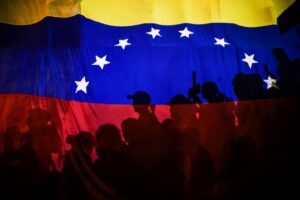Opposition protesters, seen behind a Venezuelan flag, during the violent opposition protests known as "guarimbas" in 2017. Photo: Juan Barreto/AFP/File photo.