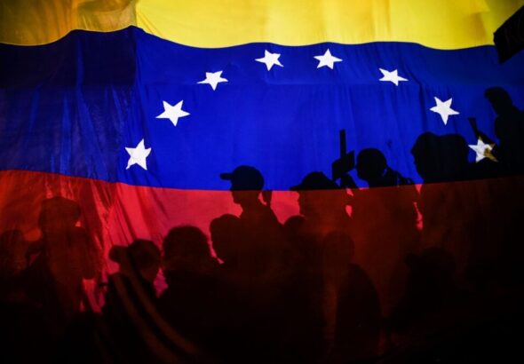 Opposition protesters, seen behind a Venezuelan flag, during the violent opposition protests known as "guarimbas" in 2017. Photo: Juan Barreto/AFP/File photo.