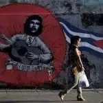 A woman walks past graffiti of revolutionary hero Ernesto "Che" Guevara and a Cuban flag by Mexican artistic group ASARO for the 12th Havana Biennial, in Havana, May 28, 2015. Photo: Enrique de la Osa/Reuters.