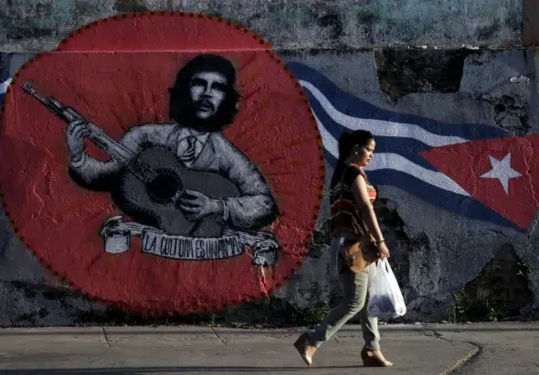 A woman walks past graffiti of revolutionary hero Ernesto "Che" Guevara and a Cuban flag by Mexican artistic group ASARO for the 12th Havana Biennial, in Havana, May 28, 2015. Photo: Enrique de la Osa/Reuters.