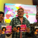 Three young people each holding the Diversity booklet, which says: Women, Dignity and Law. Photo: El 19 Digital.