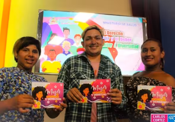 Three young people each holding the Diversity booklet, which says: Women, Dignity and Law. Photo: El 19 Digital.